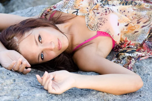 Portrait of a young blue-eyed woman lying on a rock