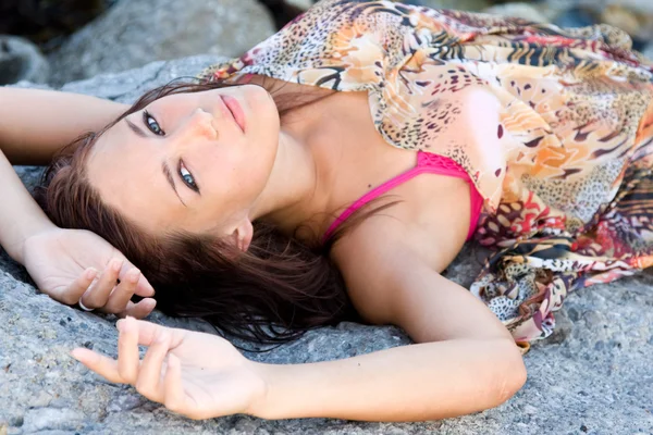 Portrait of a young blue-eyed woman lying on a rock