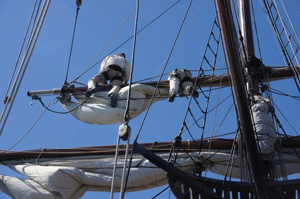Crew unfurls a sail