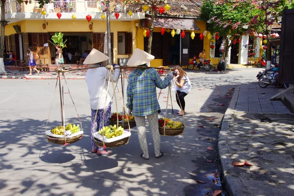 Two women carrying fruit