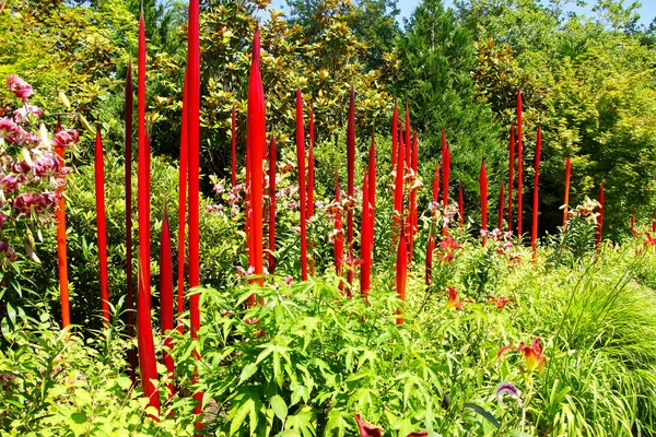 Red blown glass tubes rise among lilie