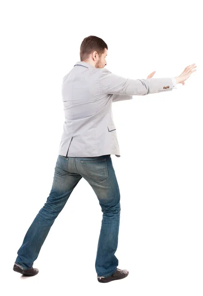 Back view of business man pushes wall.