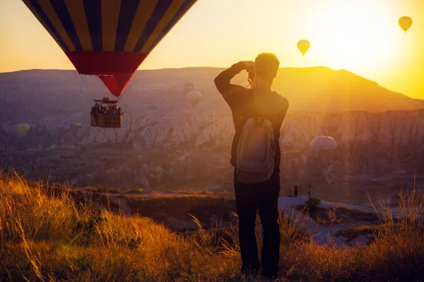 Man taking picture of air balloons