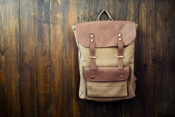 Canvas and leather backpack on wooden background