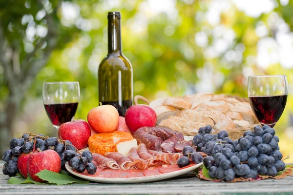 Country life setting with wine, fruits, cheese and meat. Outdoor