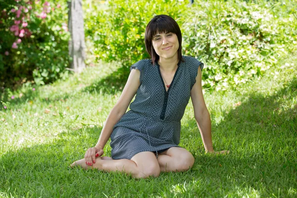 Young casual woman posing seated, smiling at the camera, outdoors
