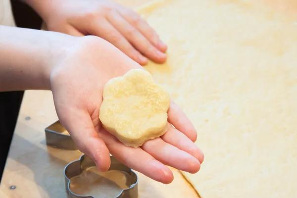 The boy carves figures out of dough