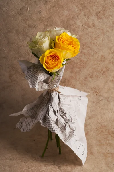 Bunch of multicolor rose flowers wrapped in newspaper over brown