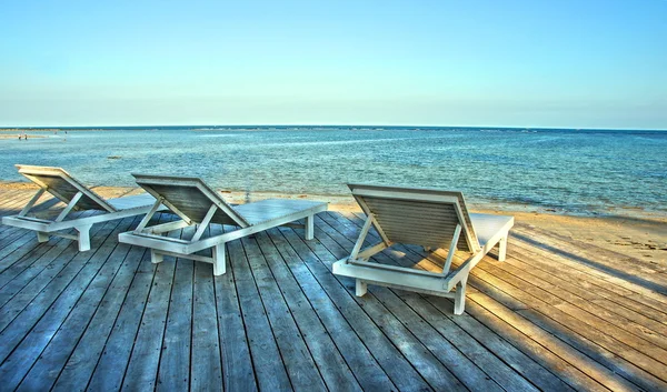 Wooden deck with chairs by beach