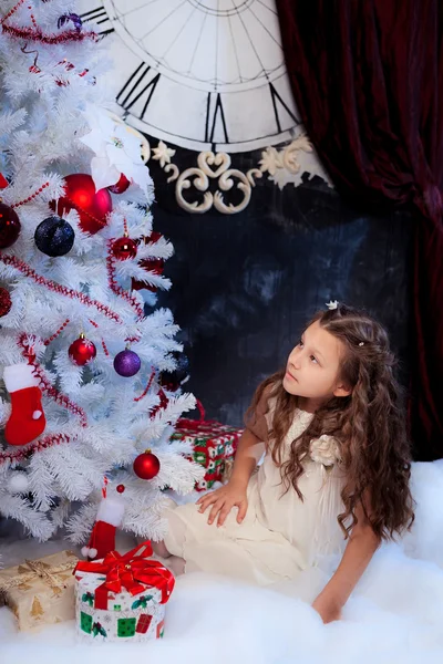 Girl looking at white Christmas tree
