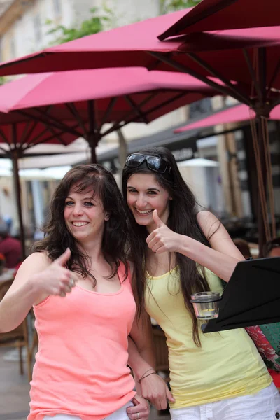 Two beautiful women giving a thumbs up