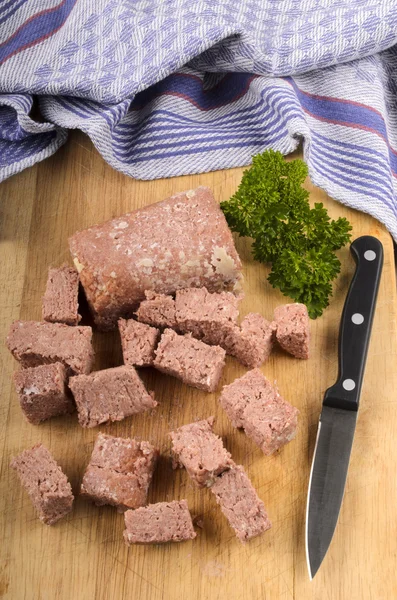 Corned beef chunks with knife on a wooden board