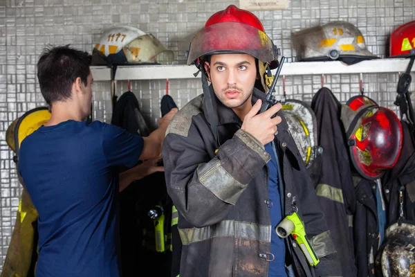 Firefighter Using Walkie Talkie With Colleague In Background
