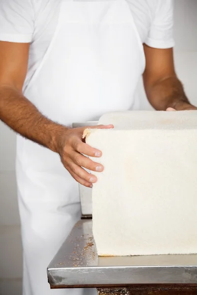 Midsection Of Baker With Bread Loaf In Bakery