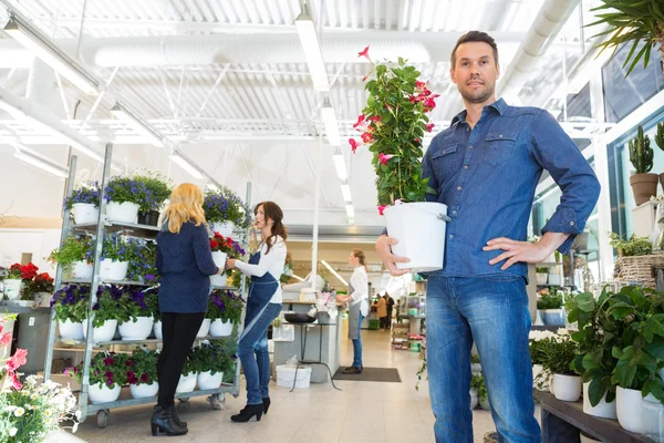 Confident Man Holding Flower Plant In Shop