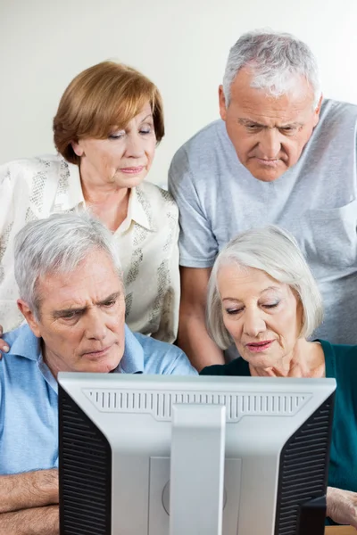 Senior People Using Computer Together In Classroom