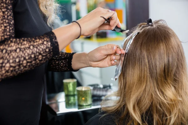 Hairdresser Highlighting Clients Hair In Salon