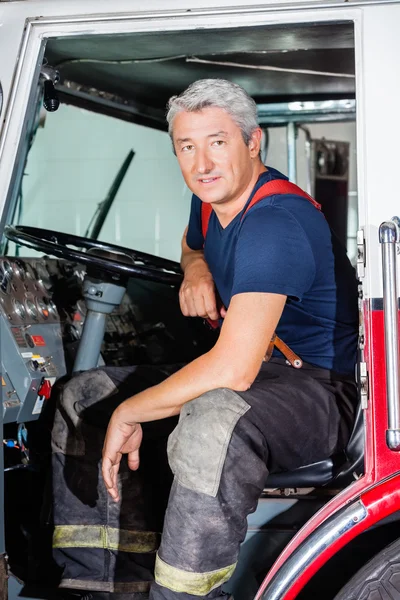 Confident Male Firefighter Sitting In Truck