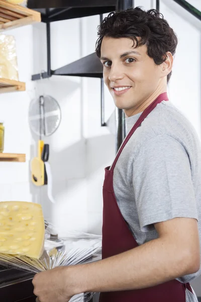 Confident Salesman Packing Cheese At Grocery Store