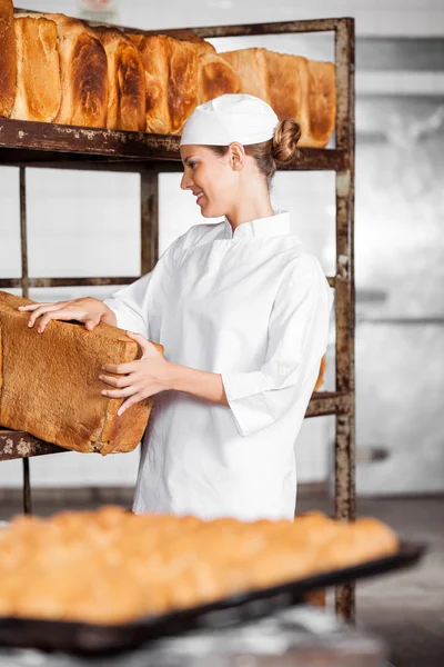 Baker In Uniform Removing Bread Loaf From Rack