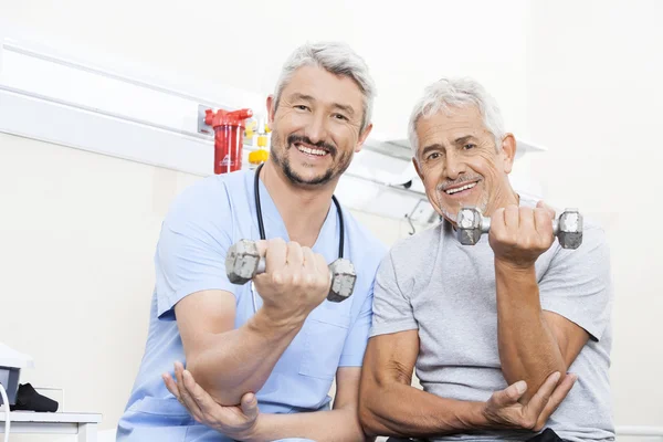 Happy Physiotherapist And Senior Patient Lifting Dumbbells