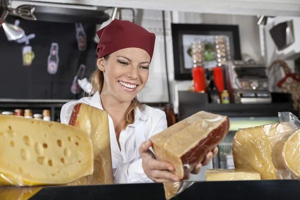 Saleswoman Holding Piece Of Cheese In Grocery Store