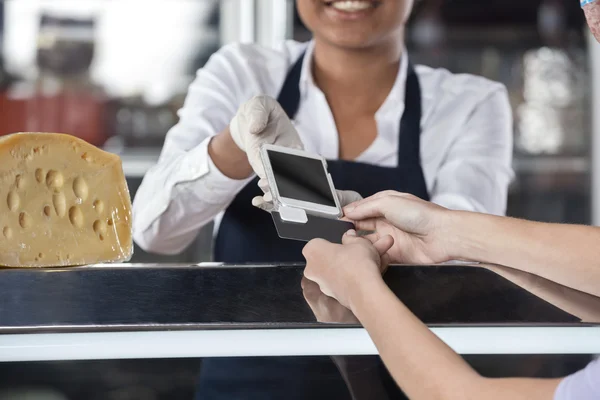 Woman Making Payment Through Credit Card At Cheese Shop