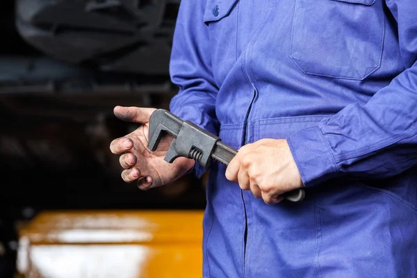 Mechanic Holding Adjustable Wrench In Garage