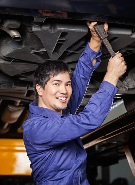 Happy Mechanic Working Underneath Lifted Car
