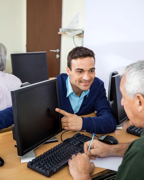 Happy Teacher Showing Something To Senior Student On Computer