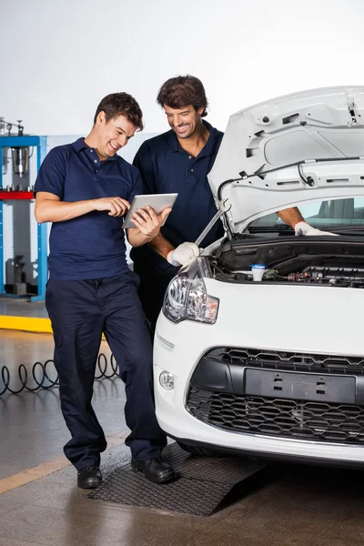 Mechanics Discussing While Using Digital Tablet By Car