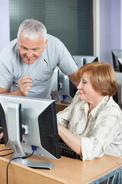 Senior Woman Showing Something To Classmate On Computer Monitor