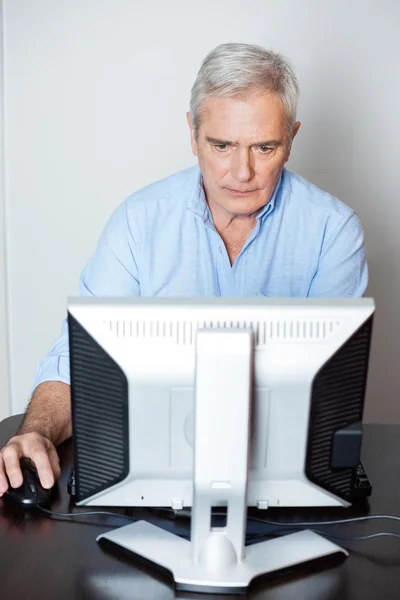 Concentrated Senior Man Using Computer In Class