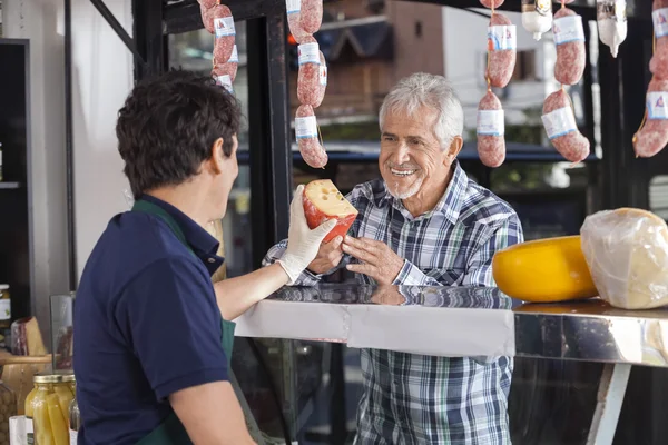Man Buying Cheese From Salesman In Shop