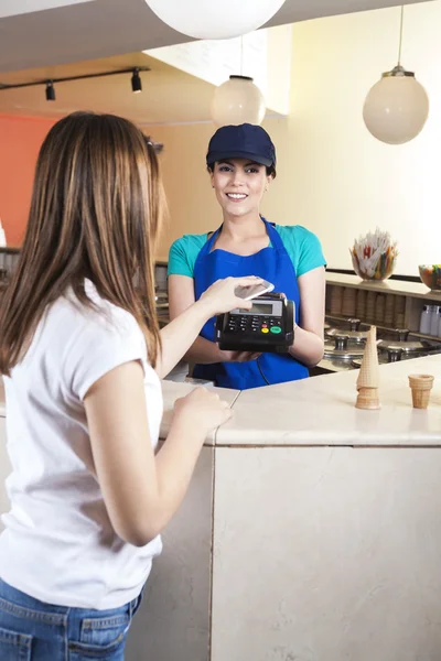 Girl Making NFC Payment On Mobile Phone While Waitress Smiling