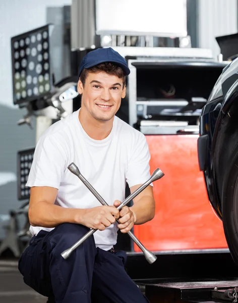 Confident Mechanic Holding Rim Wrench At Garage