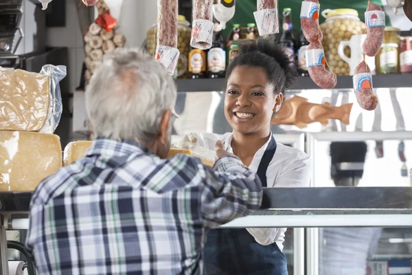 Happy Saleswoman Selling Cheese To Male Customer