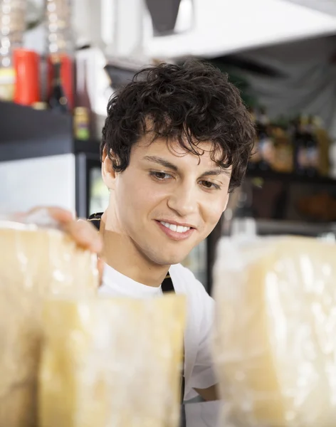 Salesman Arranging Cheese In Shop