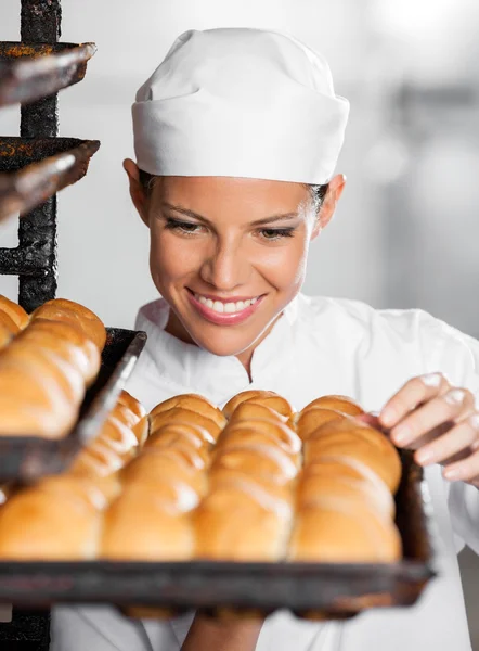 Baker Looking At Freshly Baked Breads In Bakery