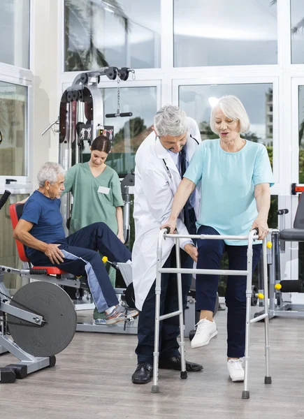 Physiotherapist Assisting Senior Woman With Walker In Fitness Ce