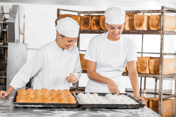 Female Bakers Analyzing Dough At Table