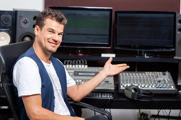 Confident Man Showing Monitors On Audio Mixing Table