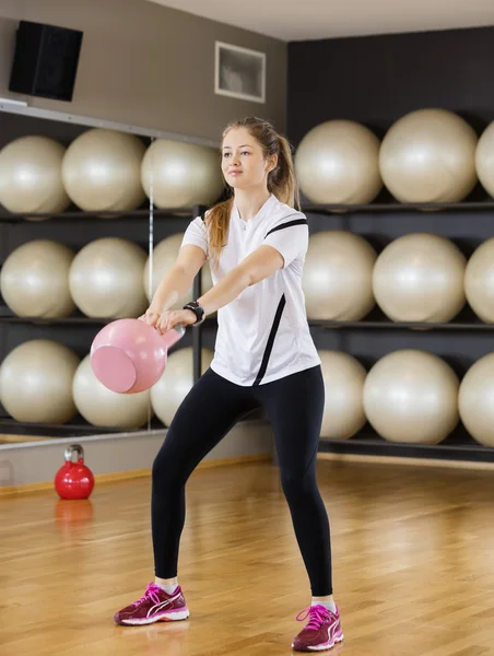 Determined Woman Lifting Kettlebell In Health Club
