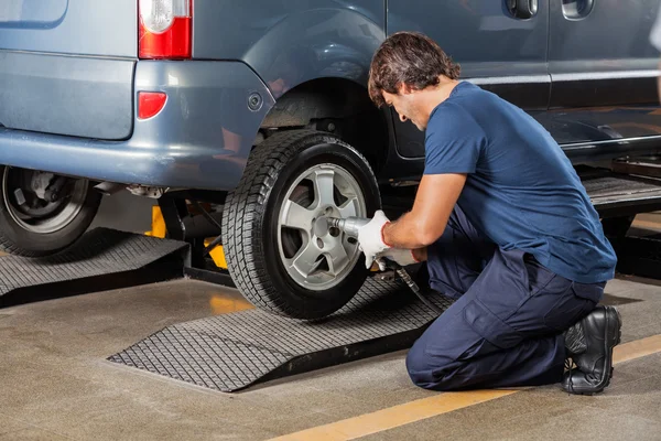 Mechanic Fixing Car Tire At Auto Repair Shop