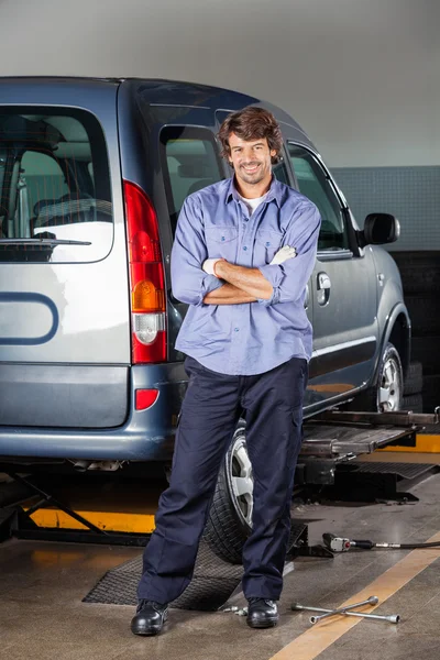 Portrait Of Mechanic Standing By Car At Garage