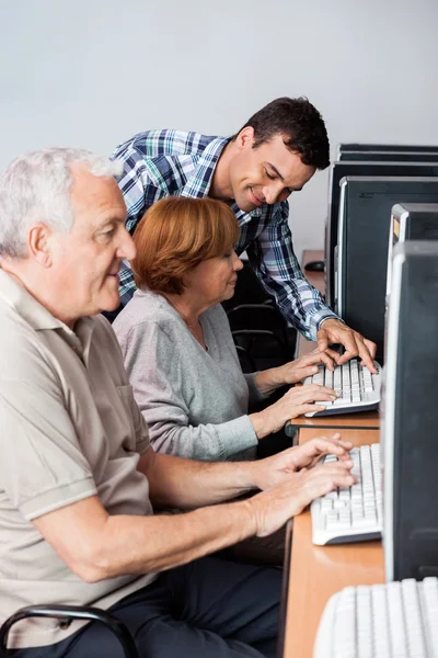 Tutor Helping Senior Woman In Using Computer