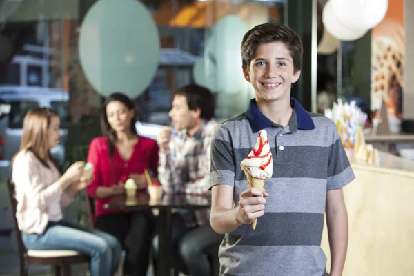 Smiling Boy Holding Vanilla Ice Cream Cone In Parlor