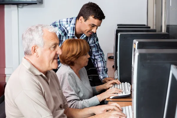 Tutor Assisting Senior Woman In Using Computer