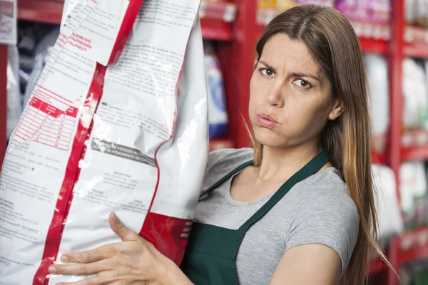Saleswoman Carrying Heavy Food Package In Pet Store