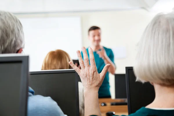 Senior Woman Raising Hand In Computer Class